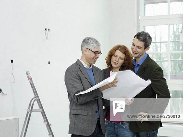 An architect going over blueprints with a young couple