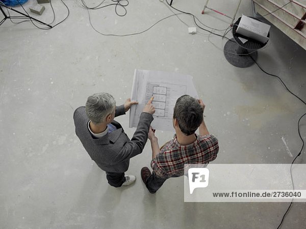 A construction worker going over blueprints with an architect