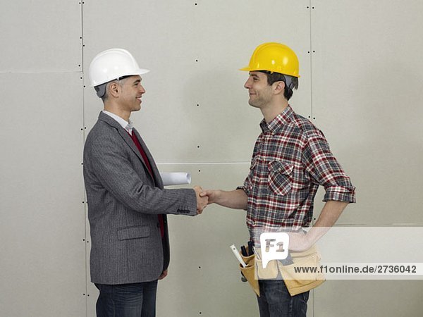 Ein Architekt schüttelt einem Bauarbeiter die Hand.