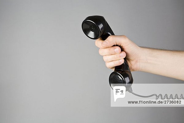 A hand holding a telephone receiver