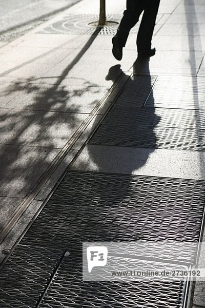 Der Schatten einer Person  die die Straße entlang geht.