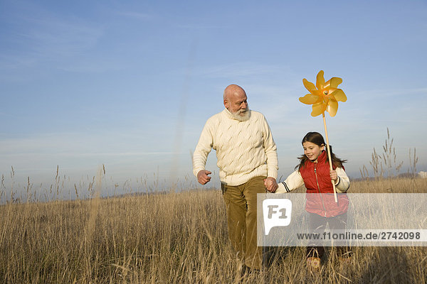 Girl holding pinwheel and running with her grandfather