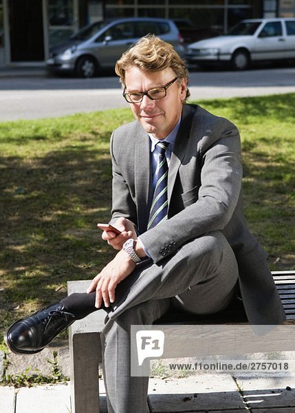Businessman with cellphone om a bench