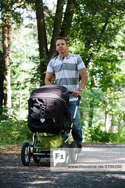Vater zu Fuß in einem Park mit Kinderwagen einen sonnigen Tag Schweden.