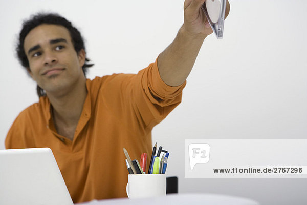Man sitting at desk  holding out CD