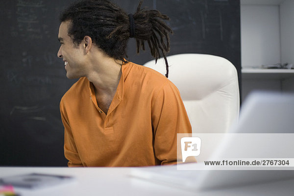 Man sitting at desk  smiling over shoulder