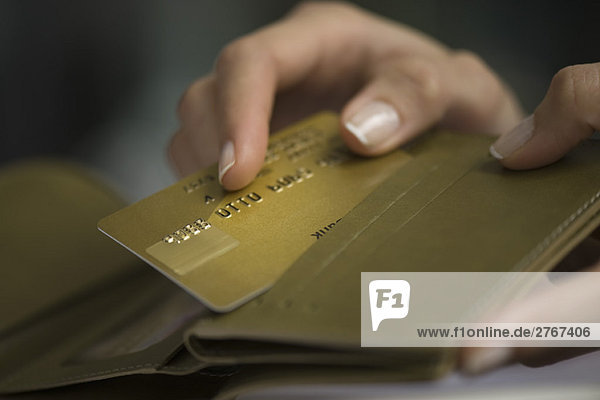 Frauenhand nimmt Kreditkarte aus der Brieftasche