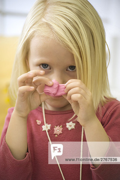 Kleines Mädchen hält rosa Ton vor dem Gesicht  Porträt