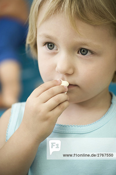 Little girl eating marshmallow