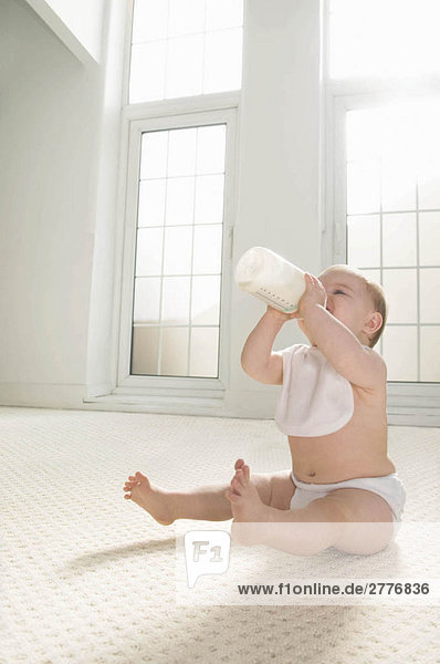 Ein Baby  das aus einer Milchflasche trinkt.