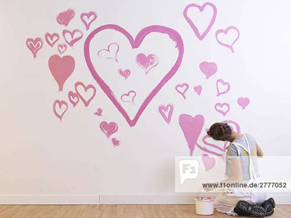 Girl paints pink hearts.