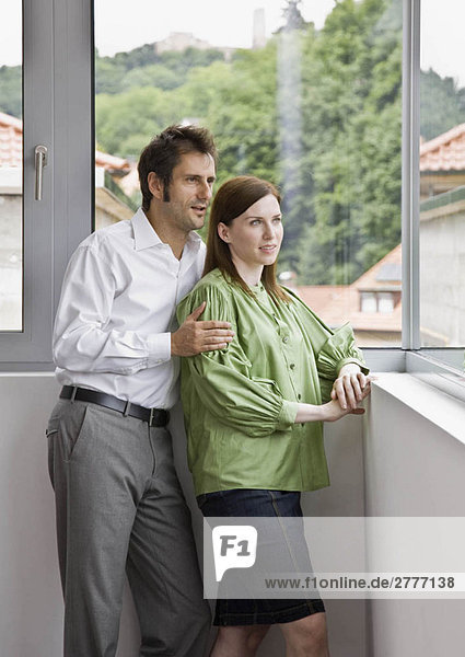 Mann und Frau schauen aus dem Fenster.