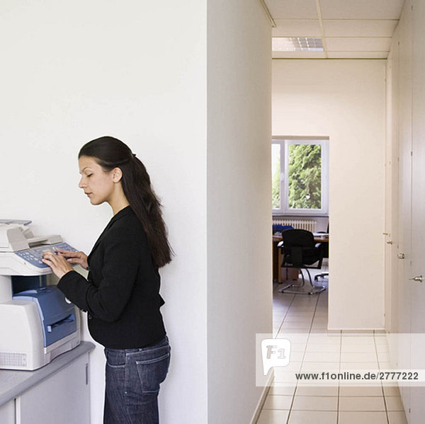 Worker using copier in busy office