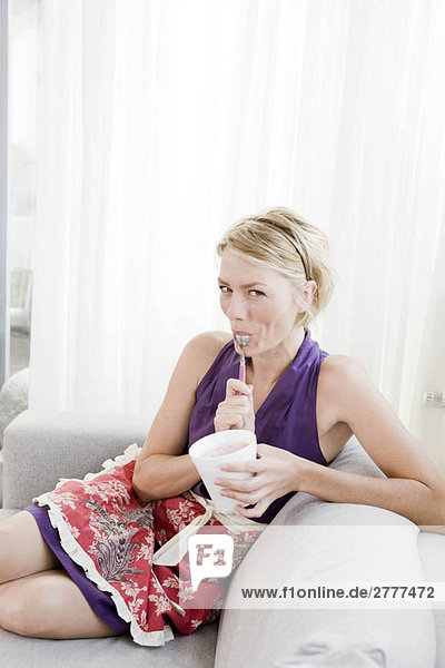 Woman on sofa eating ice cream