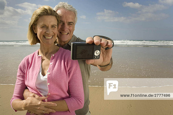 Paar beim Fotografieren am Strand