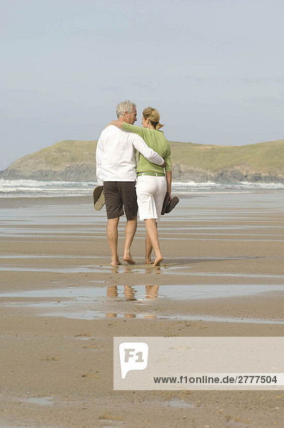 Couple walking arm in arm on a beach