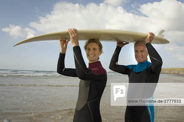 Paar mit Surfbrett am Strand