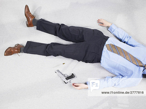 Mann auf dem Boden liegend mit Pistole