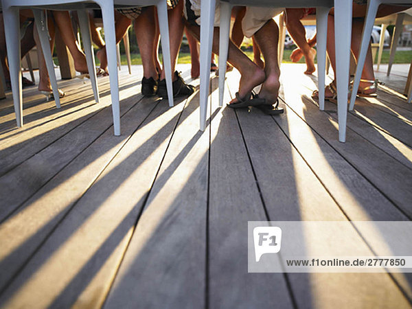 Viele Beine unter dem Tisch werfen Schatten.