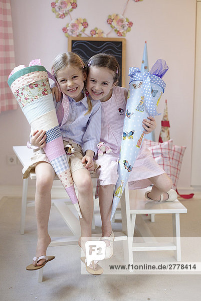 Portrait von zwei Mädchen Pappe Zapfen hält und lächelnd auf Tabelle