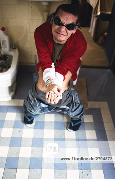 Man using toilet  grimacing
