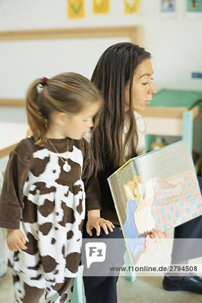 Lehrer liest Buch vor  Kind steht in der Nähe