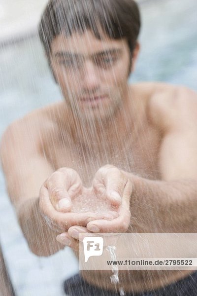 Junger Mann steht unter der Dusche