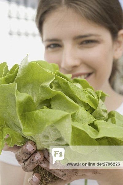 Junge Frau hält frischen Kopfsalat aus dem Garten