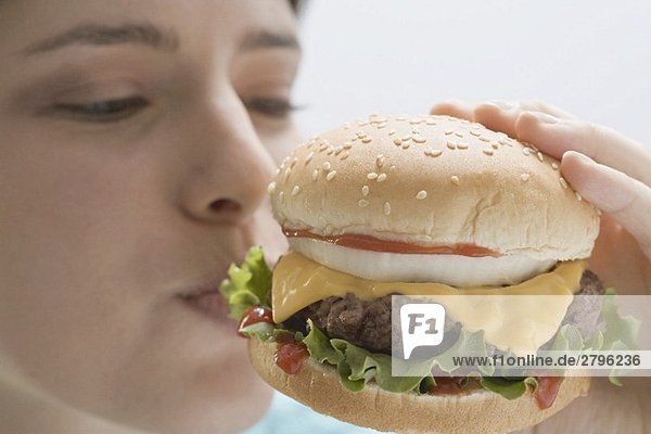 Junge Frau beisst in Cheeseburger