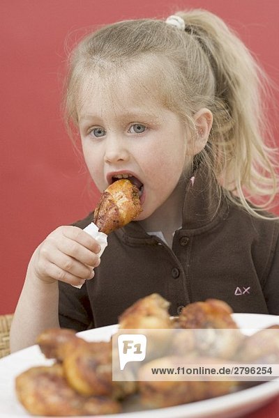 Kleines Mädchen isst Hähnchenkeule