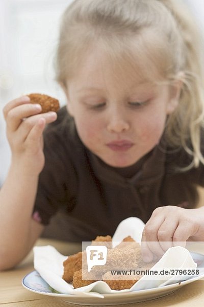 Kleines Mädchen isst Chicken Nuggets