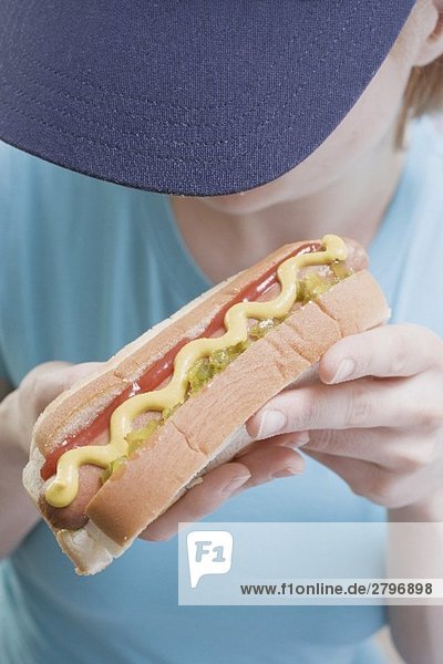 Frau hält Hot Dog mit Senf  Relish und Ketchup