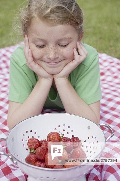 Mädchen betrachtet Erdbeeren im Fussseiher