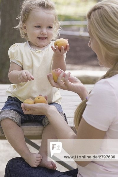 Mutter und kleine Tochter halten frische Aprikosen