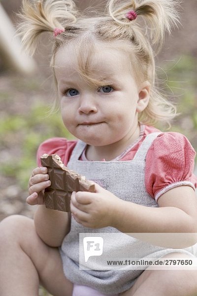 Kleines Mädchen hält angebrochene Tafel Nussschokolade