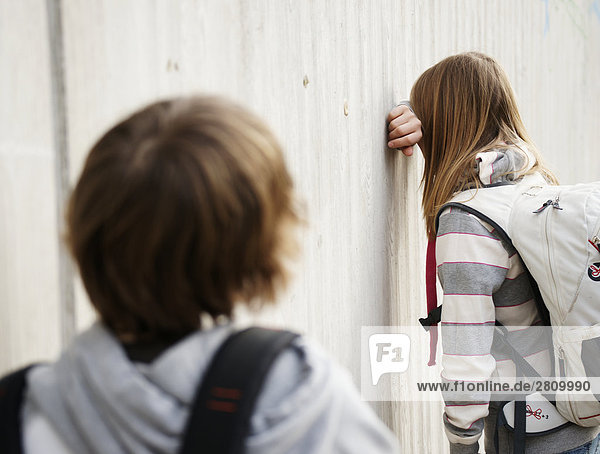 Grundschule Schüler über ihr Gesicht gegen Wand