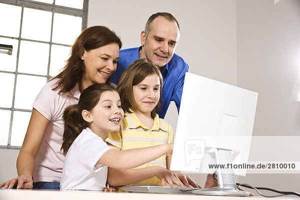 Familie lächelnd beim auf Computer-Bildschirm ansehen