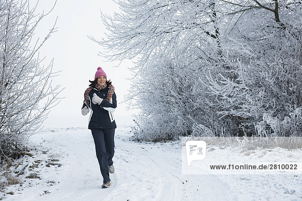 Woman walking in snow covered landscape
