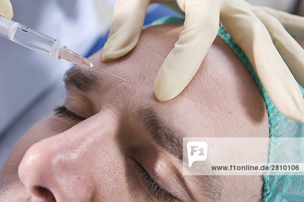 Chirurg Injektion in die Stirn des Patienten