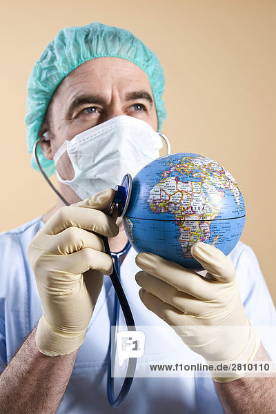 Male surgeon examining globe with stethoscope