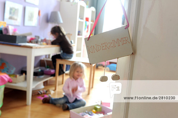 Schild an Tür des Zimmers mit zwei Mädchen Studium im Hintergrund