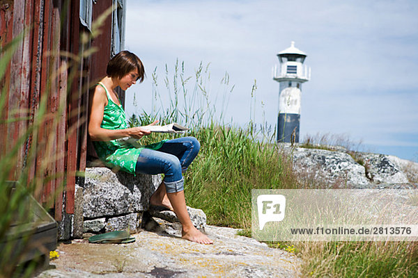 A Scandinavian woman sitting by a house in the archipelago Sweden.