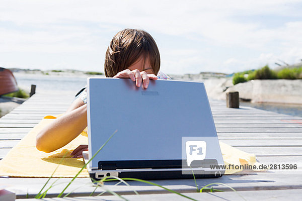 Eine skandinavische Frau mit einem Laptop in den Schären Schweden.