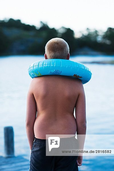 Ein Junge mit einem aufblasbaren schwimmen Ring auf einer Mole Schweden.