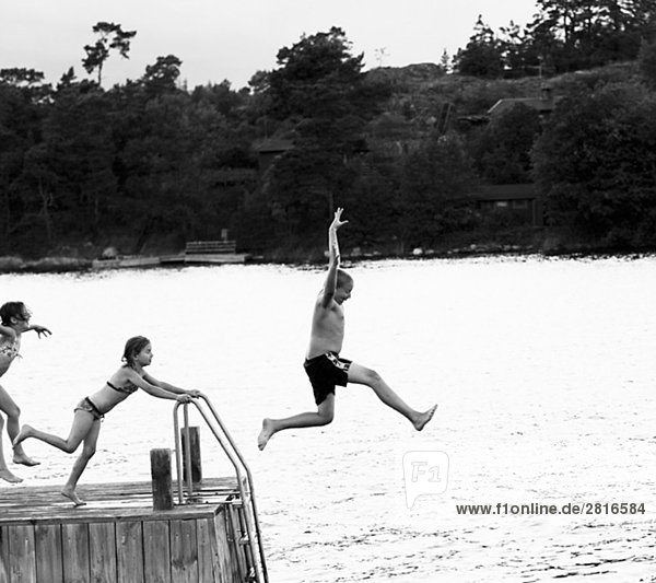 Three children jumping from a jetty Sweden.