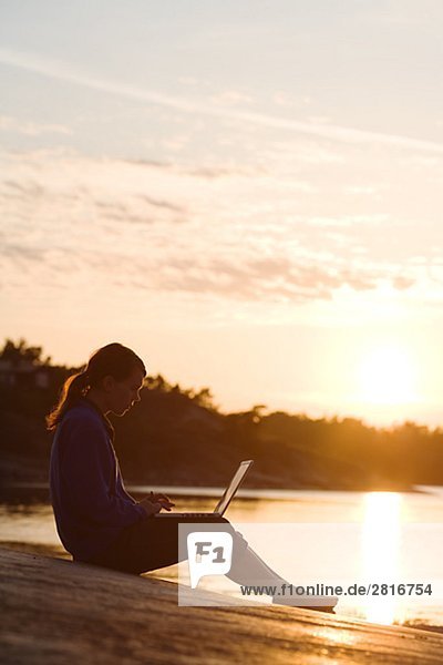 Eine Frau mit einem Laptop Stockholmer Schären in Schweden.