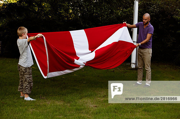 Ein Mann und ein Junge Faltung der dänische Flagge Kopenhagen Dänemark.