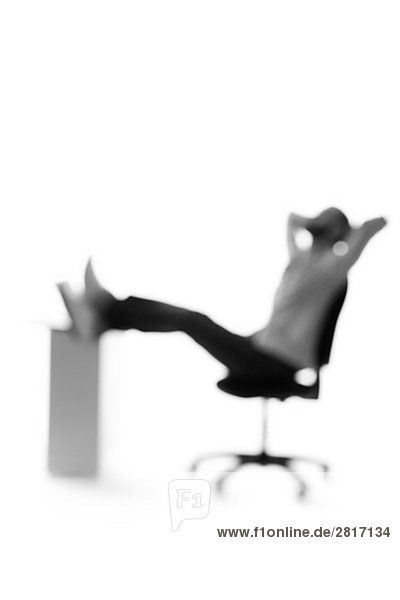 Silhouette eines Mannes von einem Schreibtisch sitzend.