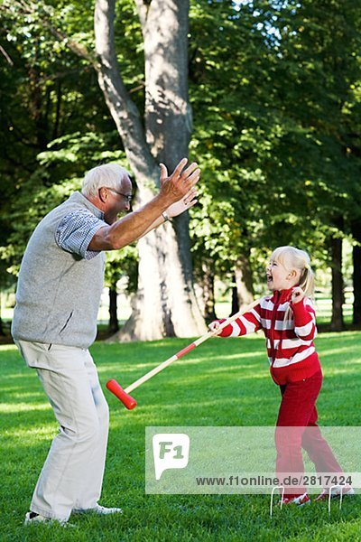 Girl and senior man playing croquet in the park Sweden.