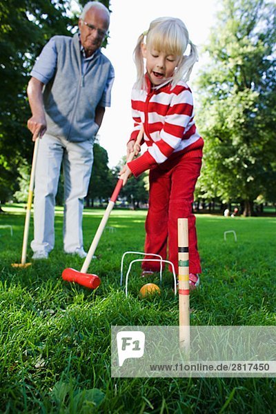 Mädchen und älterer Mann spielen Krocket im Park Schweden.